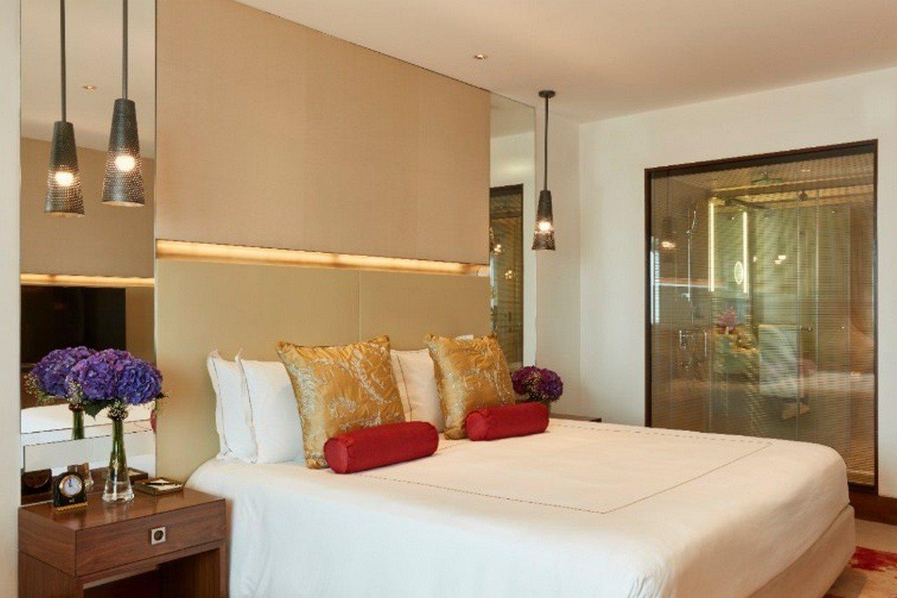 The Taj Mahal Tower, Mumbai Hotel Ngoại thất bức ảnh The photo shows a modern bedroom with a stylish design. It features a large bed with white linens and decorative pillows in gold and red. The walls are neutral, and there are pendant lights hanging above the bed. To the side, there is a wooden nights