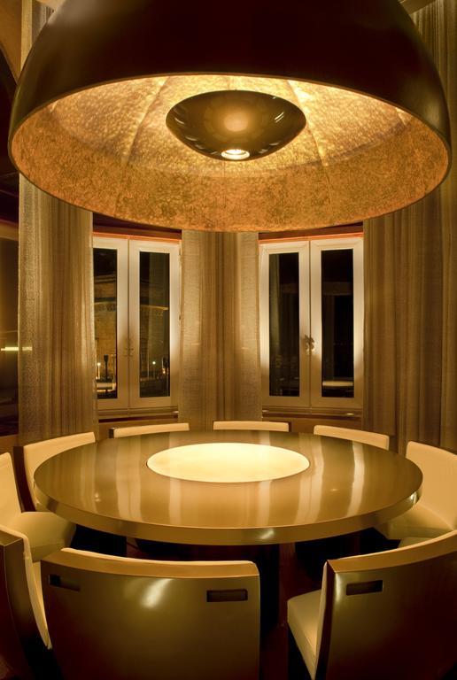 The Taj Mahal Tower, Mumbai Hotel Ngoại thất bức ảnh The photo shows a modern dining room with a round table at the center. The table has a glossy surface and features a circular illuminated section in the middle. Surrounding the table are sleek, contemporary chairs. The room has large windows dressed 