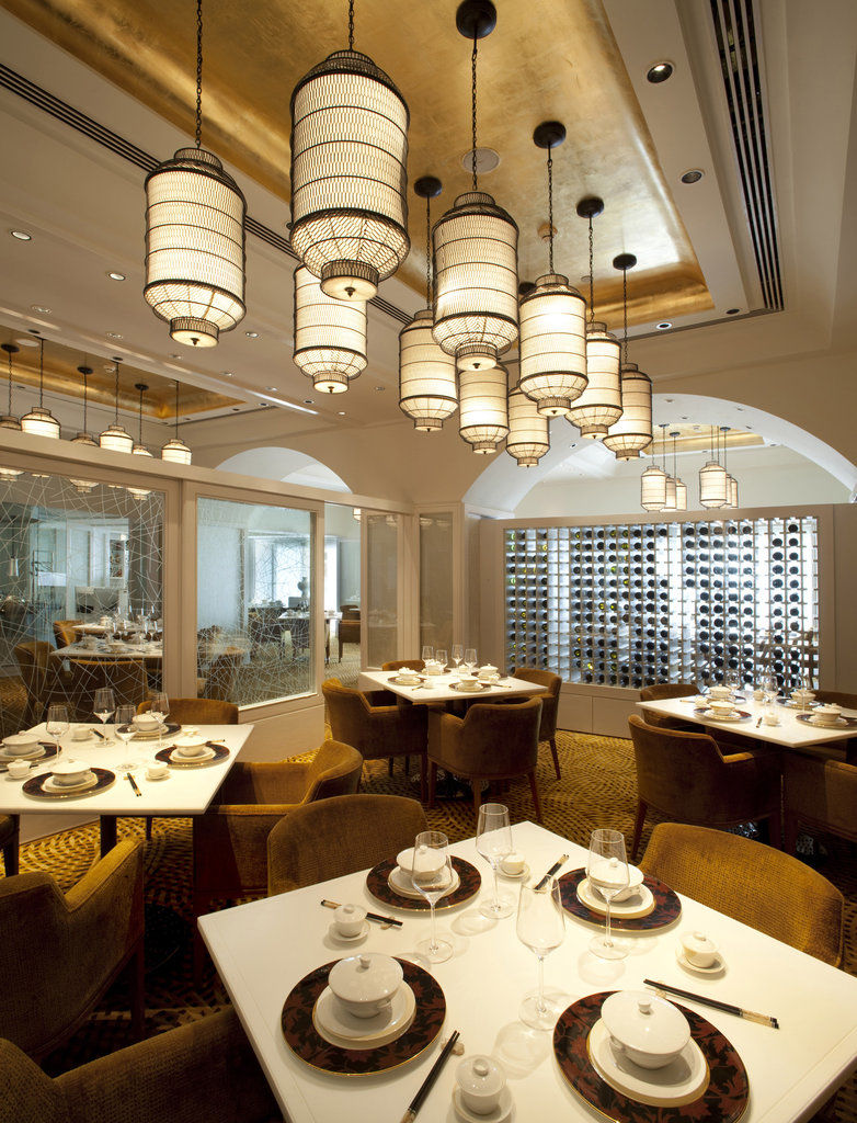 The Taj Mahal Tower, Mumbai Hotel Ngoại thất bức ảnh The photo depicts an elegant restaurant interior. It features a sophisticated design with multiple hanging light fixtures that have a distinct, stylish appearance. The tables are round and set for dining, with neatly arranged plates and utensils. The